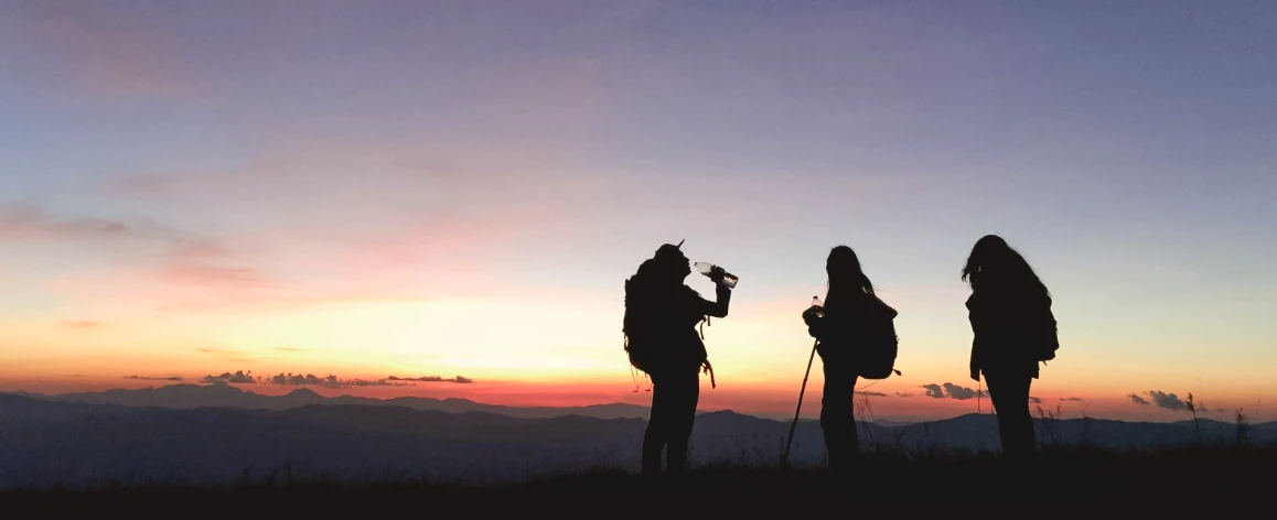 A photo of 3 people hiking at sunset